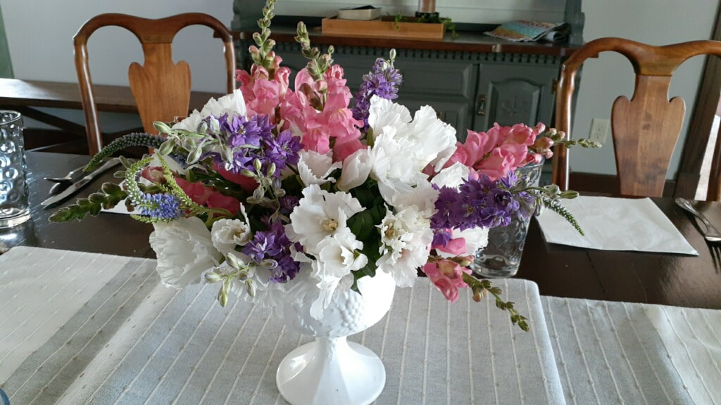 purple white and pink elegant flower arrangement in white pedestal vase